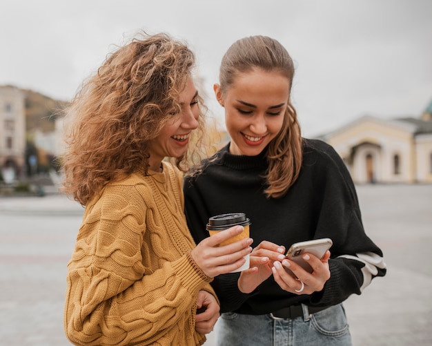 Bastante jovencitas revisando un teléfono juntos