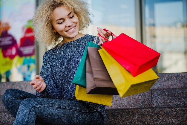 Bastante mujer sentada con bolsas de papel