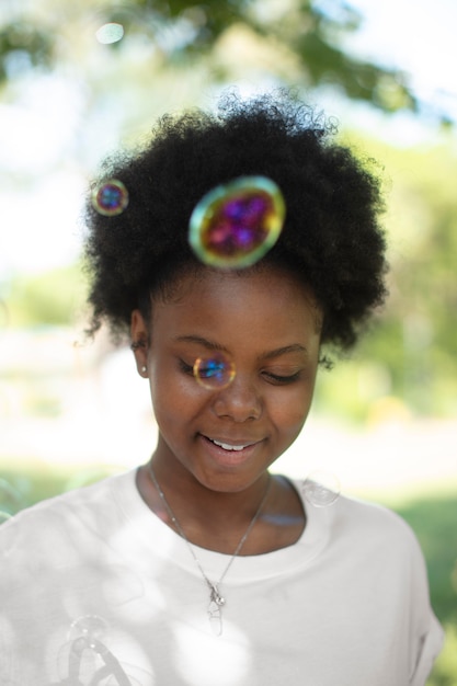 Foto gratuita bastante negra adolescente jugando con pompas de jabón