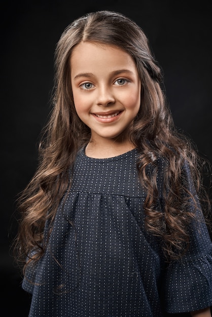 Bastante pequeña modelo en hermoso vestido gris posando, sonriendo.