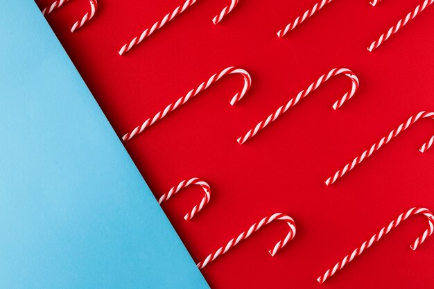 Bastón de caramelo de Navidad sobre fondo de papel rojo y azul