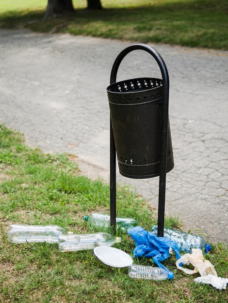 Foto gratuita basura plástica cerca del contenedor metálico en el parque