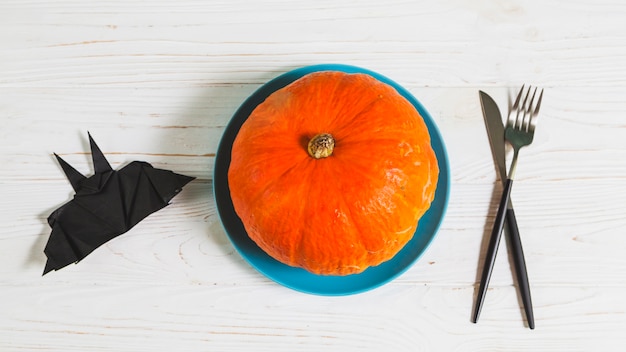 Foto gratuita bat origami y calabaza en plato de pie en el escritorio de madera