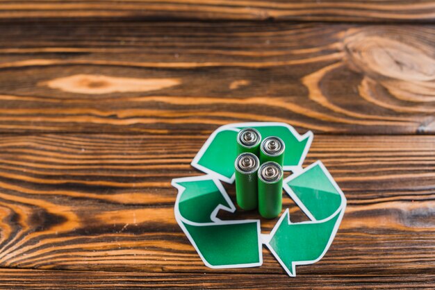 Batería en el icono de reciclaje sobre fondo de madera con textura