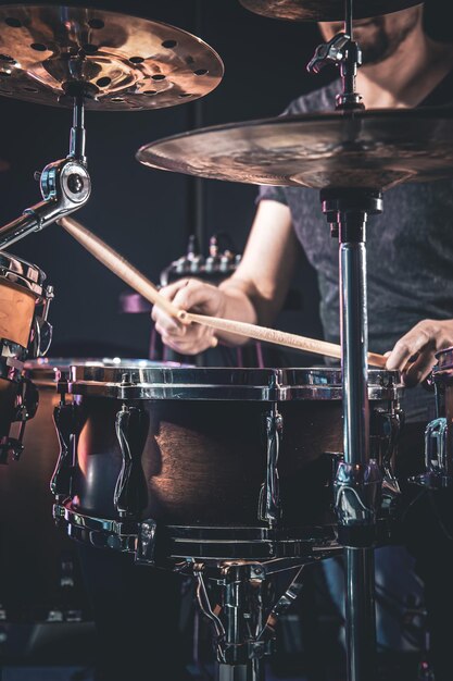 Un baterista masculino toca la batería en un cuarto oscuro