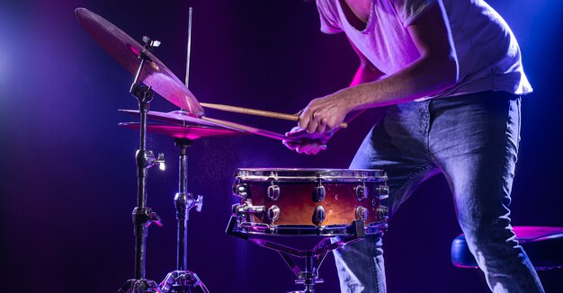 Un baterista toca la batería en una pared azul