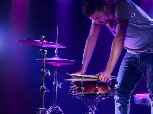 Un baterista toca la batería en una pared azul