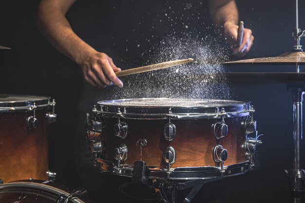 El baterista toca el tambor con salpicaduras de agua.