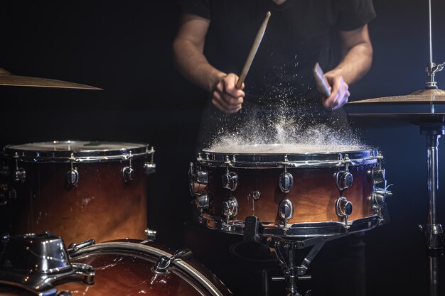 El baterista toca el tambor con salpicaduras de agua.