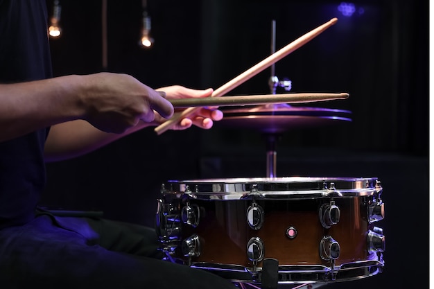 El baterista tocando baquetas en un tambor en la oscuridad. Concepto de concierto y actuación en directo.