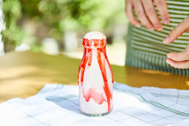 Batido de fresa en la mesa de madera junto a las manos del hombre.