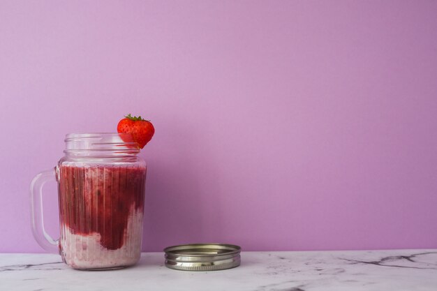 Batido de fresa en tarro contra fondo rosa