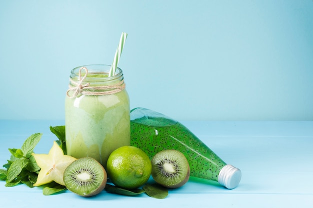 Batido de frutas verde y jugo sobre fondo azul