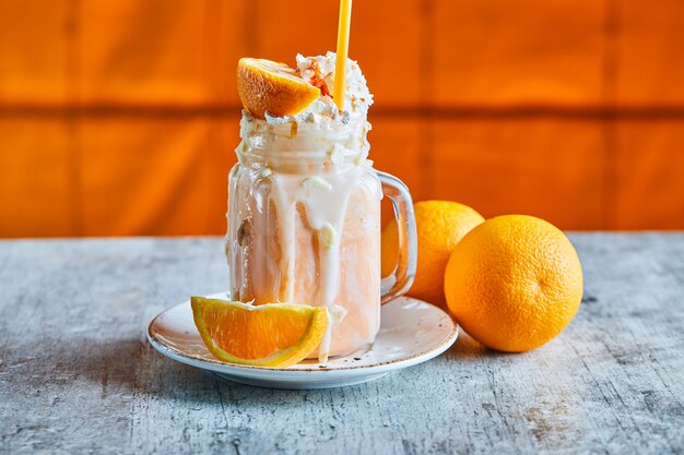 Batido de naranja con chispas y paja en la placa blanca.