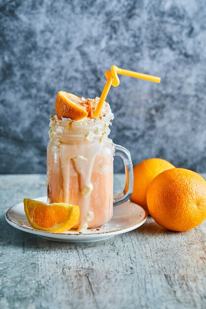 Batido de naranja con chispas y paja en la placa blanca.