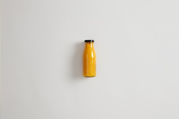 Batido de naranja mango piña fresco casero en botella de vidrio aislado sobre fondo blanco. Combinación equilibrada de carbohidratos, fibra, proteínas y grasas saludables. Bebida que mantiene el déficit calórico