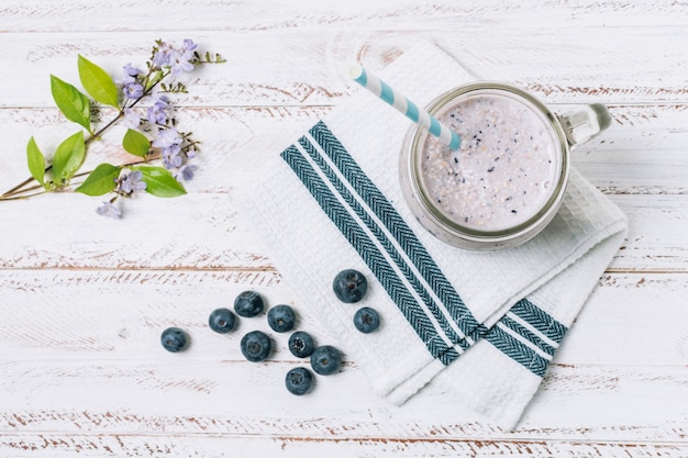 Batido plano de arándanos junto a la flor.