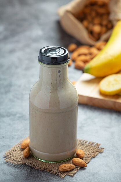 Batido de plátano y almendra en botella sobre fondo oscuro