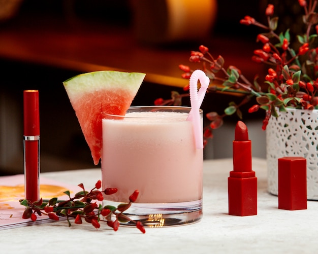 Batido de sandía adornado con sandía, junto al lápiz labial rojo