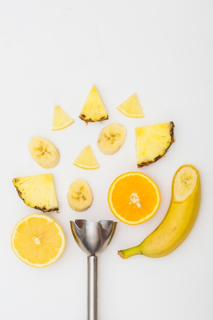 Batidora eléctrica con piña; Rodajas de plátano y naranja aisladas sobre fondo blanco