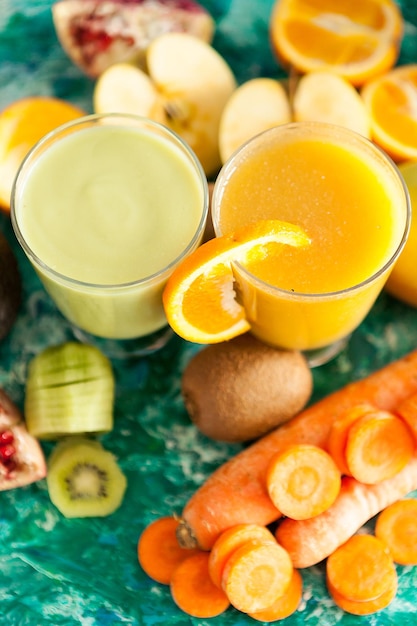 Batidos de desintoxicación crudos saludables junto a frutas y verduras sobre fondo de madera