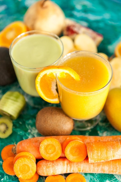 Batidos de desintoxicación frescos orgánicos rodeados de frutas y verduras sobre fondo de madera