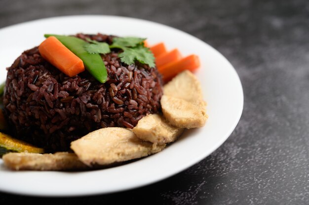 Bayas de arroz morado cocidas con pechuga de pollo a la parrilla. Calabaza, zanahorias y hojas de menta en un plato, comida limpia.