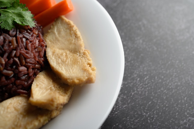 Bayas de arroz morado cocidas con pechuga de pollo a la parrilla. Calabaza, zanahorias y hojas de menta en un plato, comida limpia.