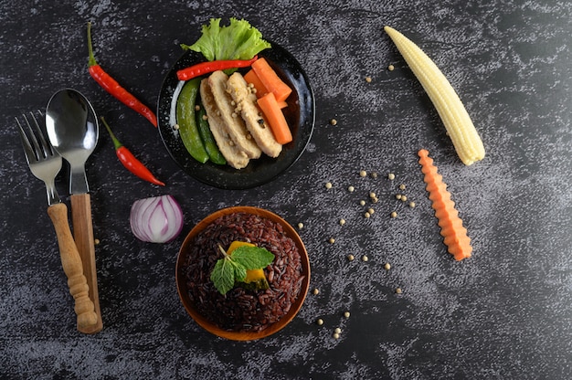 Bayas de arroz morado cocidas con pechuga de pollo a la parrilla. Calabaza, zanahorias y hojas de menta en un plato, comida limpia.