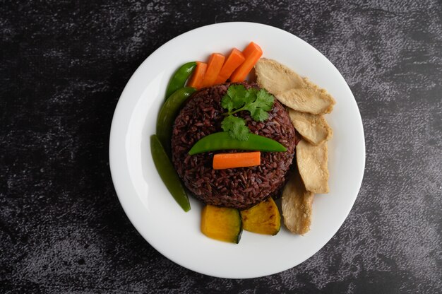 Bayas de arroz morado cocidas con pechuga de pollo a la parrilla. Calabaza, zanahorias y hojas de menta en un plato, comida limpia.