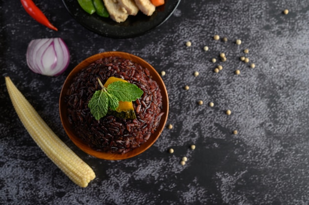 Bayas de arroz morado cocinado en un plato de madera con hojas de menta. enfoque selectivo