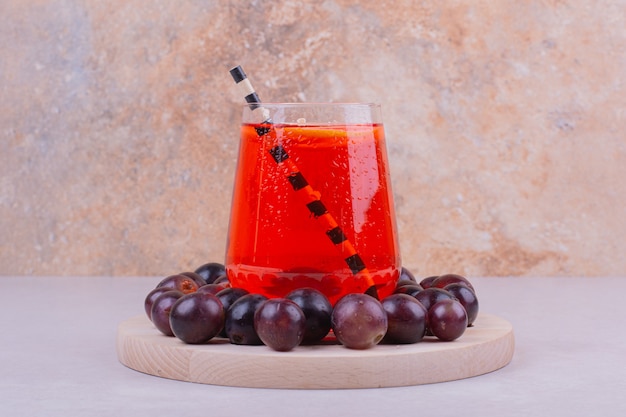 Foto gratuita bayas de cereza roja con un vaso de jugo en gris.