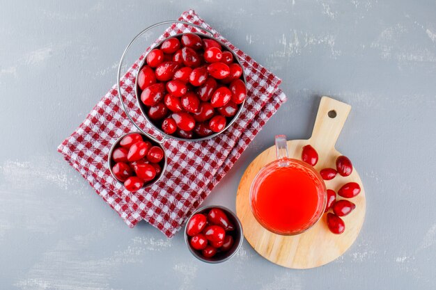 Bayas de cornejo con bebida, tabla de cortar en cubos sobre yeso y tela de picnic