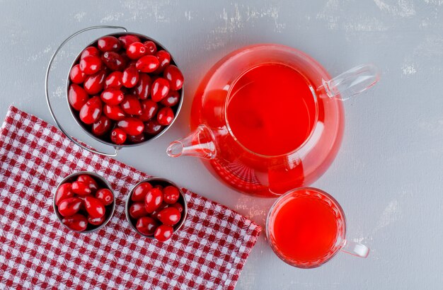 Bayas de cornejo en cubos con bebida sobre yeso y tela para picnic