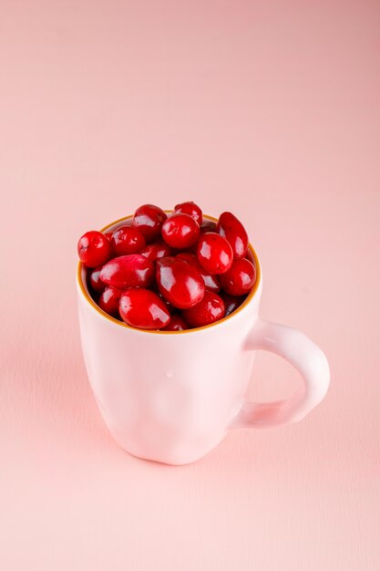 Bayas de cornejo en una taza de color rosa. vista de ángulo alto.