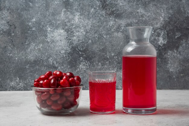 Bayas de cornel rojo en un vaso con jugo a un lado.