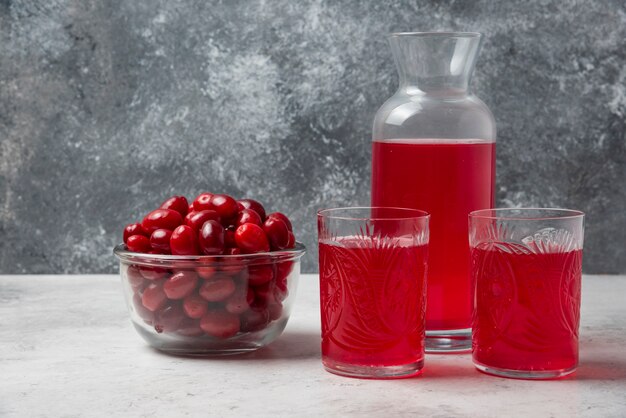 Bayas de cornel rojo en un vaso con jugo a un lado.