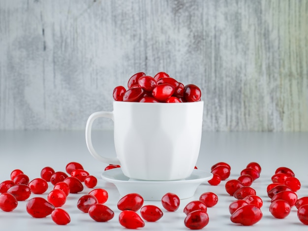 Foto gratuita bayas de cornel en una taza con platillo vista lateral en gris y blanco