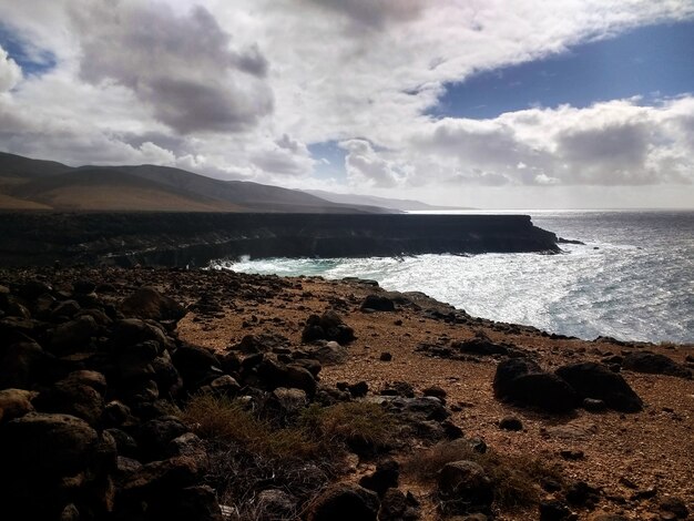 Beauitful shot playa de arena en Fuerteventura, España cubierto de rocas