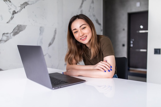 Beautifu joven mujer asiática con portátil en la cocina