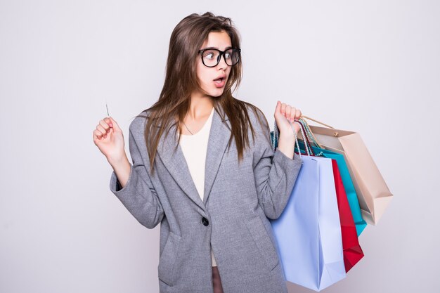 Beautilful joven llevando bolsas de compras con tarjeta de crédito aislado sobre fondo blanco.