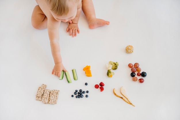 Foto gratuita bebé de ángulo alto eligiendo qué comer solo