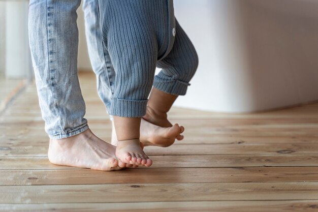 Bebé aprendiendo a caminar y siendo ayudado por su madre