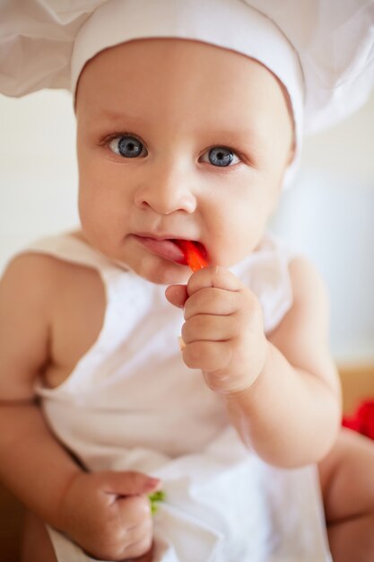 El bebé bonito comiendo un papel rojo