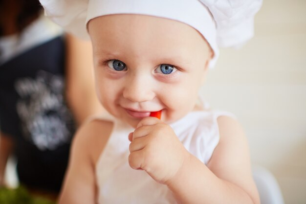 El bebé bonito comiendo un papel rojo