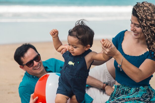 Bebé dando los primeros pasos con la madre en la playa.