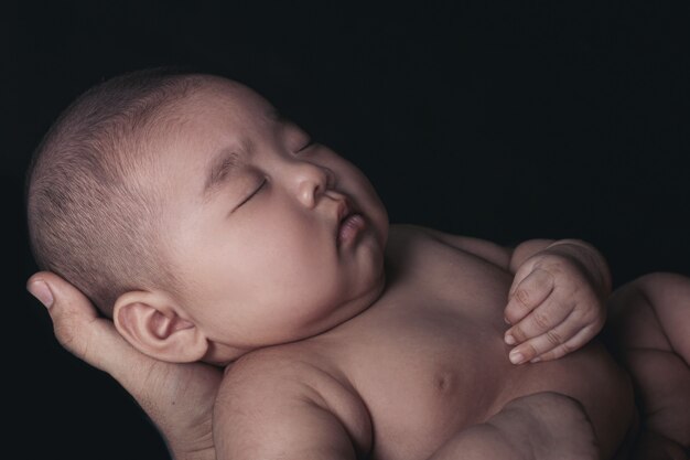 El bebé duerme en manos de un padre fuerte.