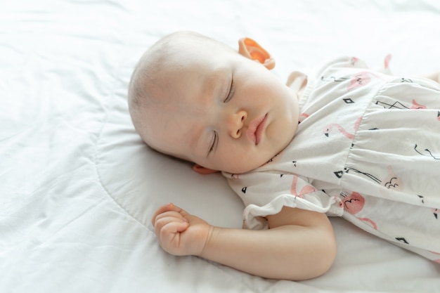 Bebé durmiendo en una cama blanca