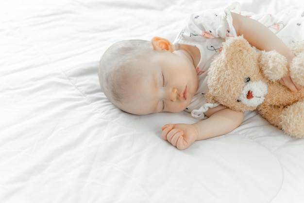 Bebé durmiendo con un oso de peluche