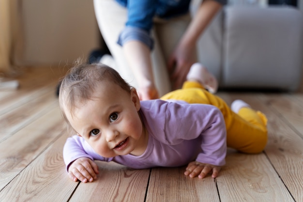 Foto gratuita bebé gateando con la ayuda de su madre